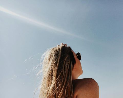 A woman wearing sunglasses basks in the sunshine.