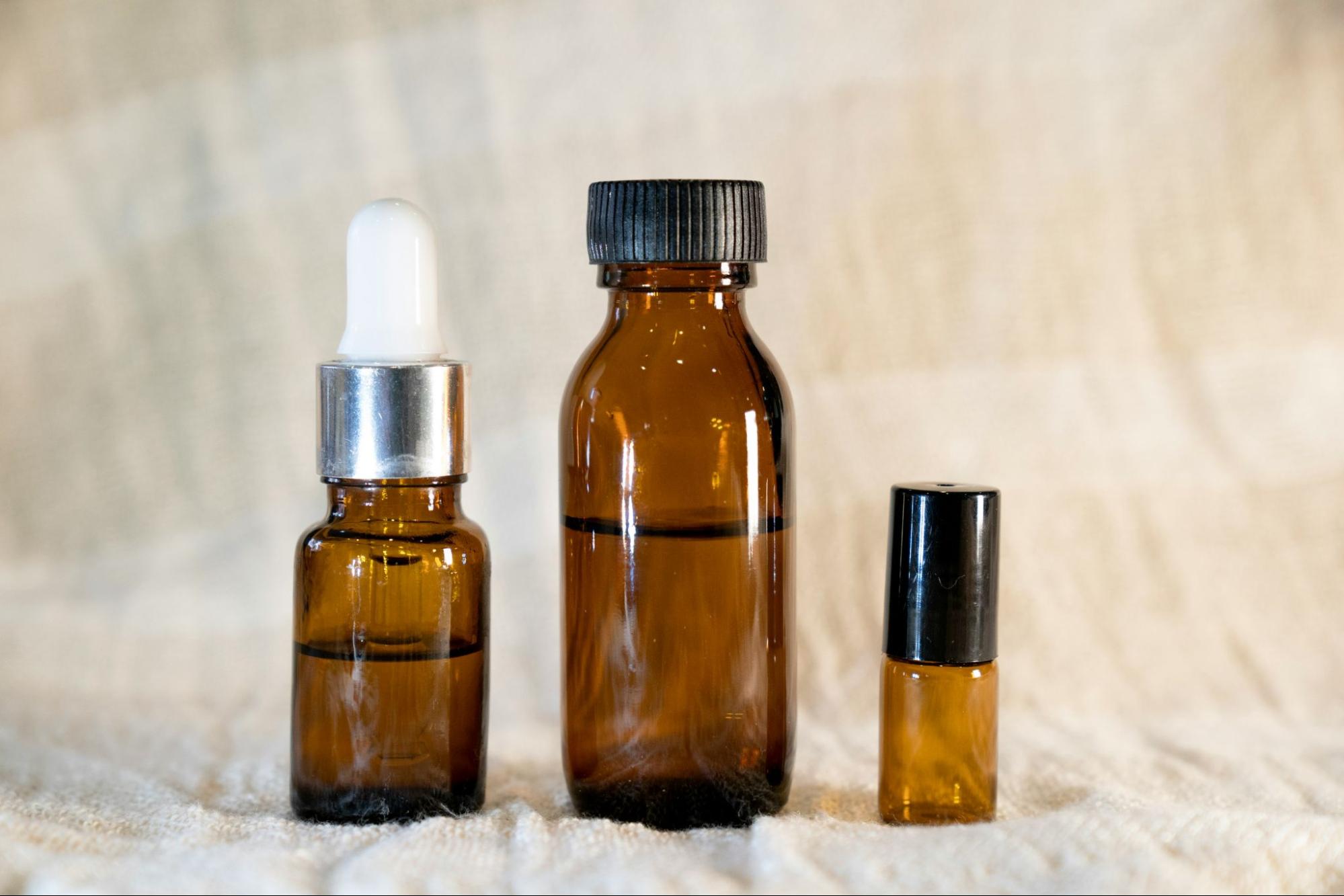 Three amber bottles of different sizes sit in a row with various amounts of serum inside.