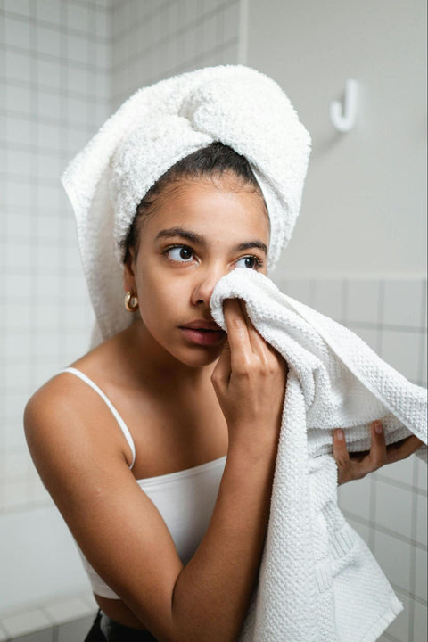 A woman dabs at her face with a white towel.